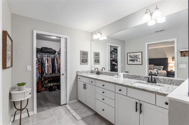 ensuite bathroom featuring double vanity, tile patterned flooring, a sink, and connected bathroom