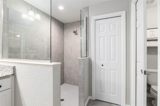 full bathroom featuring tile patterned floors, vanity, toilet, and a walk in shower