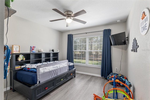 bedroom featuring a ceiling fan, baseboards, and wood finished floors