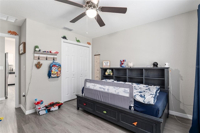 bedroom with baseboards, visible vents, a closet, and wood finished floors