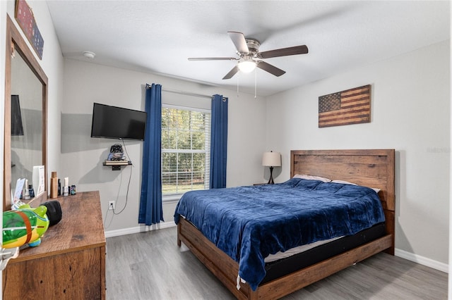 bedroom with ceiling fan, baseboards, and wood finished floors