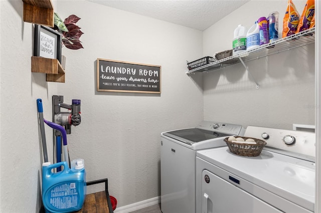 clothes washing area featuring laundry area, baseboards, a textured ceiling, and washing machine and clothes dryer