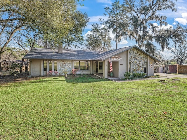 view of front of home featuring stone siding, a front yard, and fence