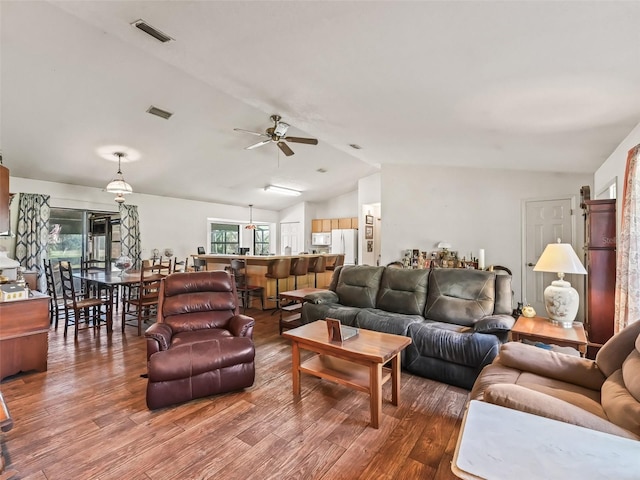 living area with lofted ceiling, ceiling fan, visible vents, and wood finished floors