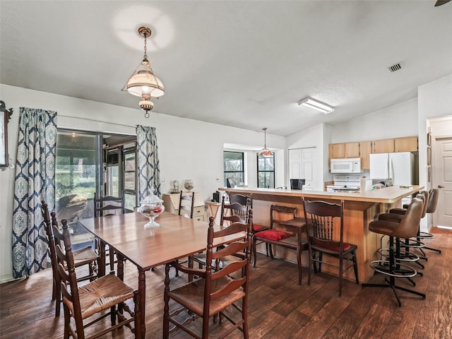 dining area with vaulted ceiling, dark wood-type flooring, and visible vents