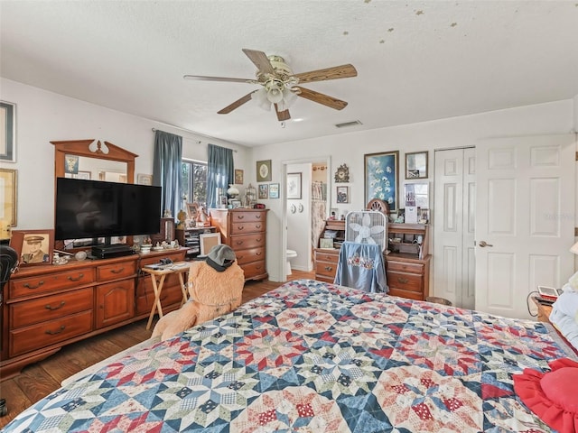 bedroom featuring a ceiling fan, visible vents, connected bathroom, and wood finished floors