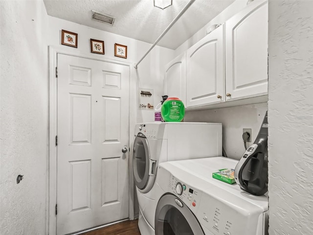 washroom featuring cabinet space, visible vents, washer and clothes dryer, a textured wall, and a textured ceiling