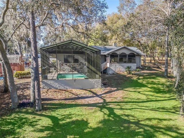 back of house with a yard, a lanai, and an outdoor pool