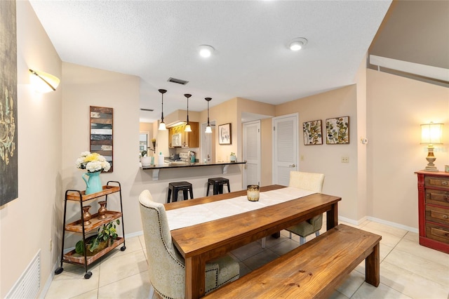 dining space featuring visible vents, a textured ceiling, baseboards, and light tile patterned floors