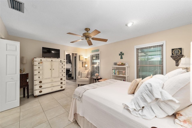 bedroom featuring visible vents, a walk in closet, a textured ceiling, a closet, and light tile patterned flooring