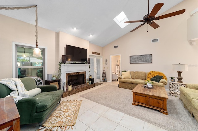 living room with light tile patterned floors, high vaulted ceiling, a fireplace, a skylight, and visible vents