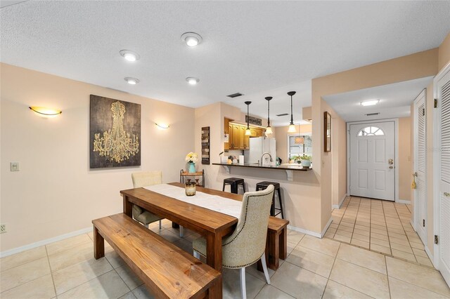 dining area with a textured ceiling, baseboards, and light tile patterned floors