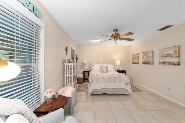 bedroom with ceiling fan, visible vents, a textured ceiling, and light tile patterned flooring