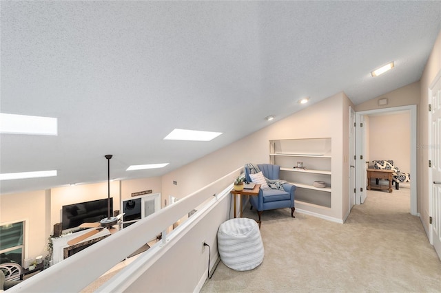 living area with a textured ceiling, lofted ceiling with skylight, and light colored carpet