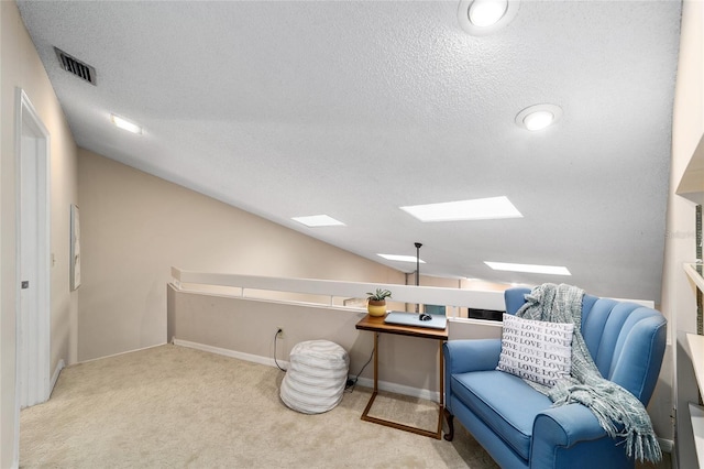 living area with vaulted ceiling with skylight, visible vents, a textured ceiling, and carpet