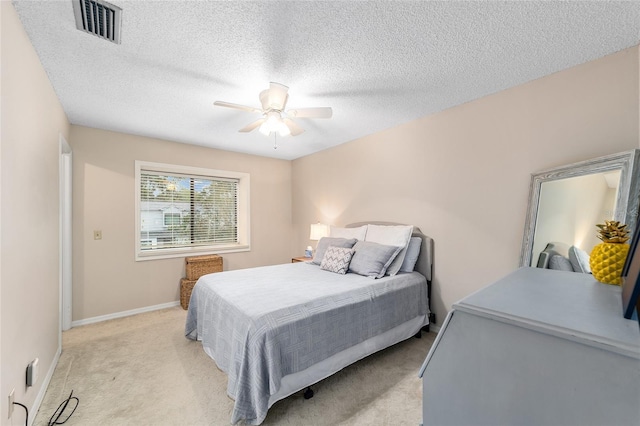 bedroom featuring light colored carpet, visible vents, a ceiling fan, a textured ceiling, and baseboards