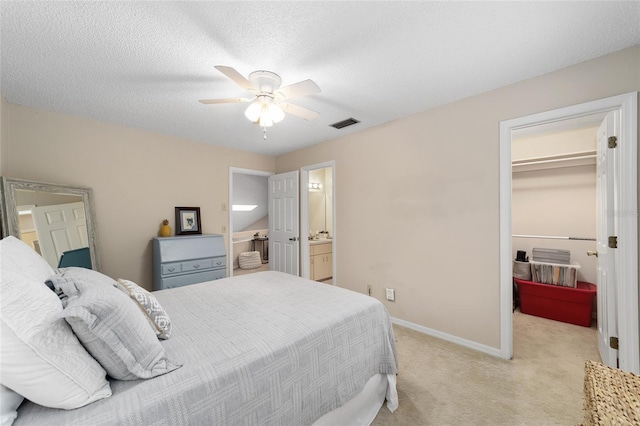 bedroom featuring visible vents, light colored carpet, a spacious closet, a textured ceiling, and baseboards