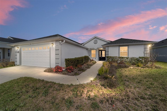 ranch-style home featuring a garage, concrete driveway, and stucco siding