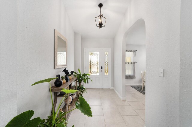 entrance foyer with light tile patterned floors, baseboards, and arched walkways