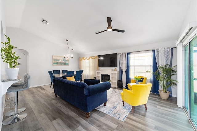 living room featuring lofted ceiling, a wealth of natural light, arched walkways, and visible vents