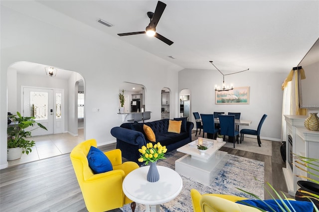 living room with visible vents, arched walkways, vaulted ceiling, and wood finished floors