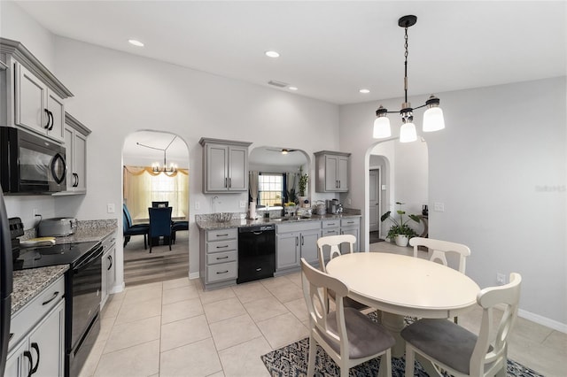 kitchen featuring arched walkways, an inviting chandelier, gray cabinets, black appliances, and light tile patterned flooring