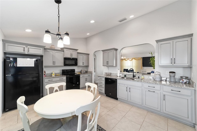 kitchen with arched walkways, gray cabinetry, vaulted ceiling, a sink, and black appliances