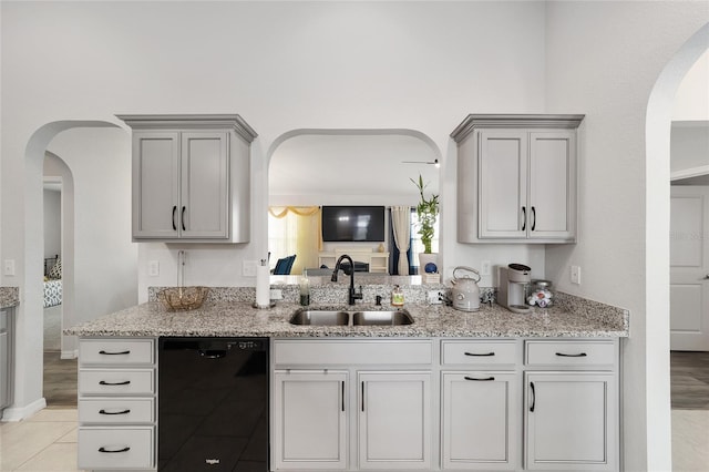 kitchen featuring black dishwasher, light stone counters, gray cabinets, and a sink