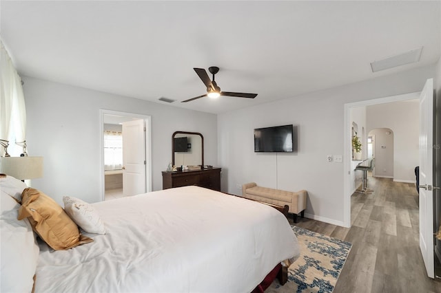 bedroom featuring baseboards, visible vents, arched walkways, ceiling fan, and wood finished floors