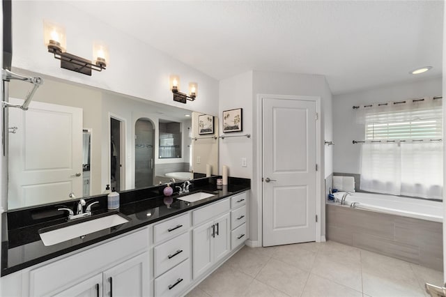 full bathroom featuring a garden tub, double vanity, tile patterned flooring, and a sink