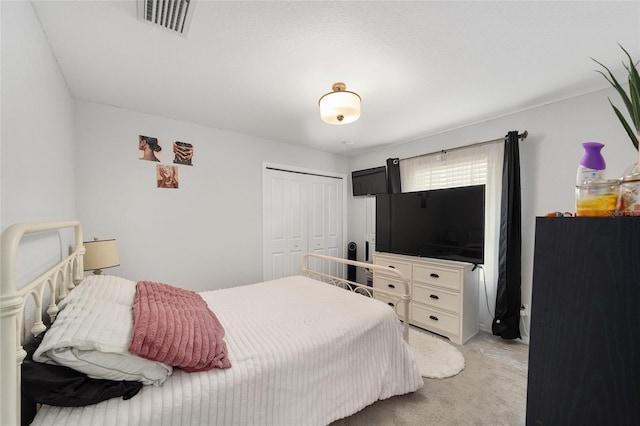 bedroom with visible vents, a closet, and light colored carpet