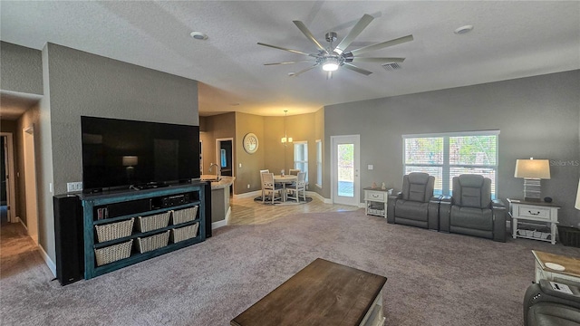 carpeted living area featuring a ceiling fan, visible vents, and baseboards