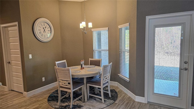 dining space featuring an inviting chandelier, baseboards, and wood finished floors