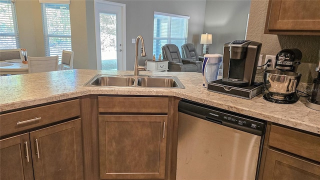 kitchen featuring a sink, open floor plan, light countertops, stainless steel dishwasher, and brown cabinets