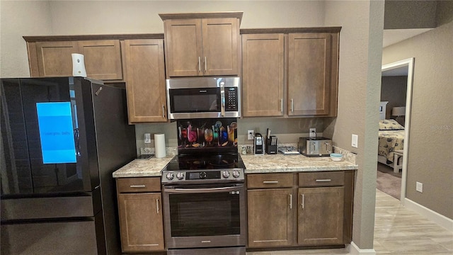 kitchen featuring baseboards, light stone counters, and stainless steel appliances