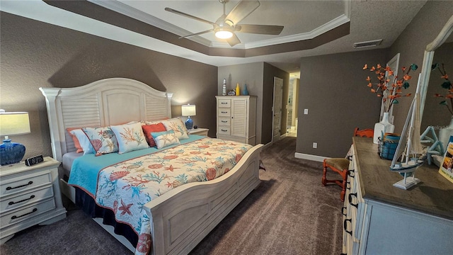 bedroom with baseboards, visible vents, ornamental molding, a tray ceiling, and dark carpet