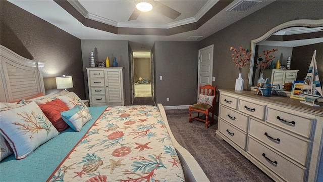 bedroom featuring baseboards, visible vents, a tray ceiling, dark colored carpet, and crown molding