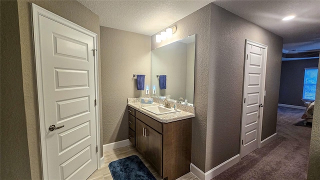 bathroom featuring a textured wall, vanity, and baseboards