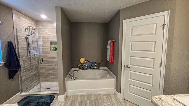 full bathroom with a textured ceiling, a shower stall, wood finished floors, baseboards, and a bath