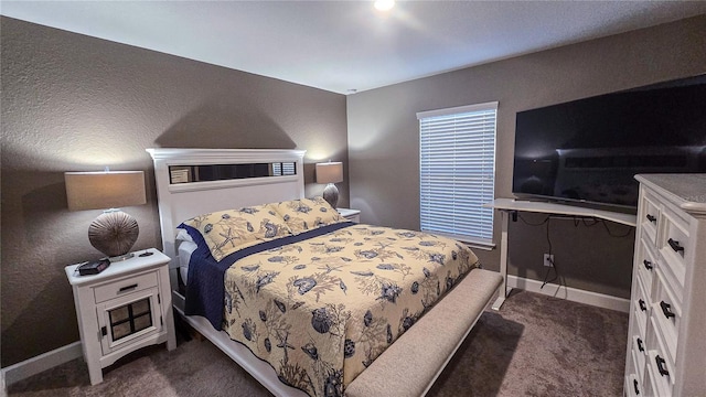 bedroom with dark carpet and baseboards