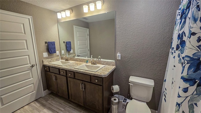 bathroom featuring wood finished floors, a sink, and a textured wall