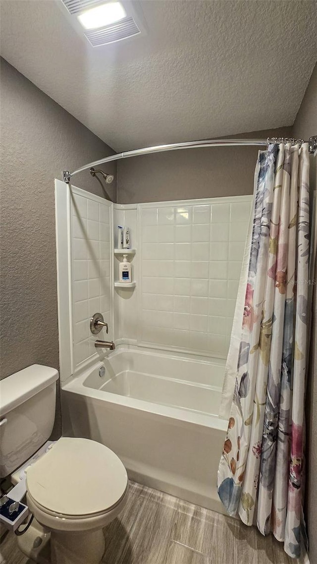 bathroom with a textured ceiling, a textured wall, toilet, visible vents, and shower / bath combo