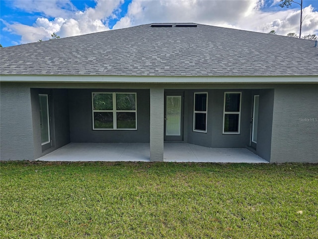 back of property featuring a yard, roof with shingles, a patio, and stucco siding