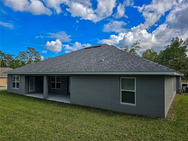 back of house featuring stucco siding, a patio area, a yard, and roof with shingles