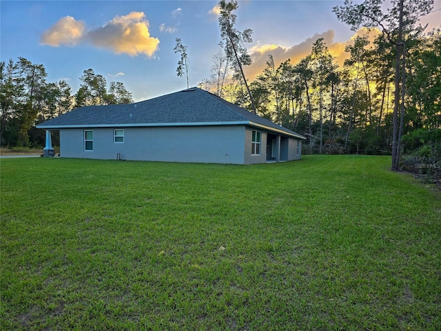 property exterior at dusk featuring stucco siding and a yard