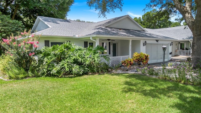 view of front of house with a front lawn, a shingled roof, an attached garage, and a ceiling fan