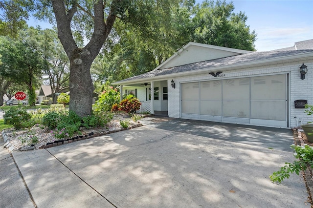 ranch-style home featuring brick siding, a shingled roof, covered porch, a garage, and driveway