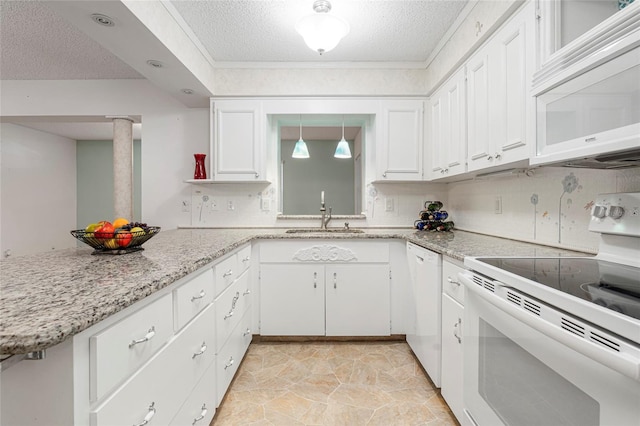 kitchen featuring a peninsula, white appliances, white cabinetry, and a sink