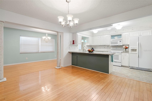 kitchen with white appliances, decorative light fixtures, a peninsula, white cabinetry, and a notable chandelier