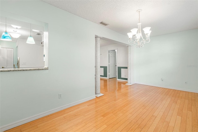 interior space with baseboards, visible vents, a textured ceiling, and light wood finished floors